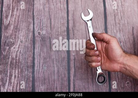 a worker's hand with a chrome-plated wrench. Stock Photo