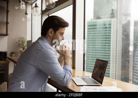 Close up thoughtful businessman wearing glasses looking at laptop screen Stock Photo