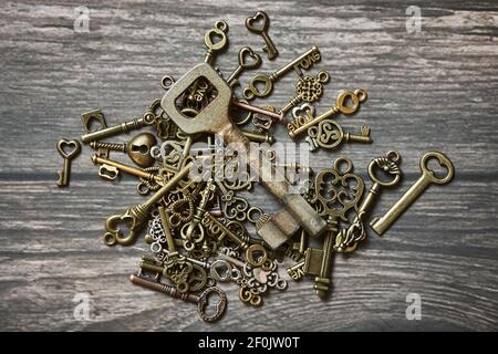 Many different small keys with love symbols and one old rusty key on wooden background. Stock Photo