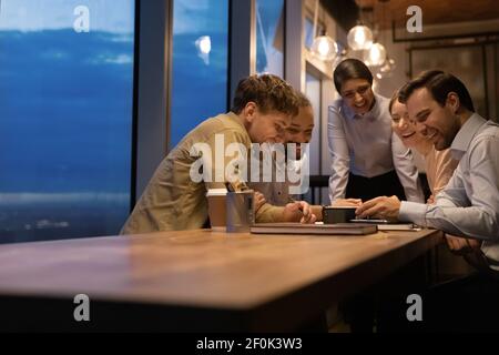 Close up overjoyed diverse colleagues looking at phone screen together Stock Photo