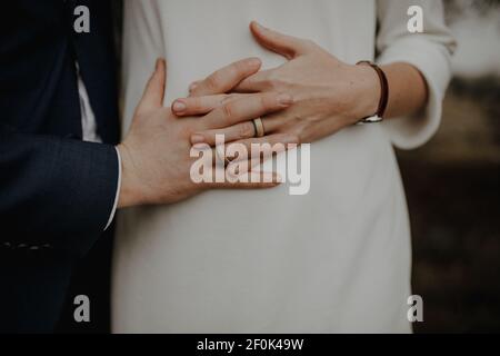 Bilder des Bauches einer schwangeren Frau. Ihre Hände und die Ihres Mannes liegen gefaltet auf ihrem runden Bauch. Stock Photo