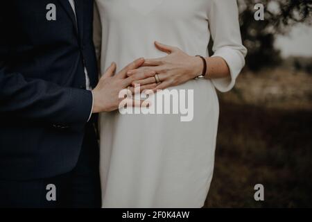 Bilder des Bauches einer schwangeren Frau. Ihre Hände und die Ihres Mannes liegen gefaltet auf ihrem runden Bauch. Stock Photo