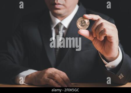 business man wearing suit and necktie holding bit coin on black background,electronic virtual money for web banking and international network payment, Stock Photo