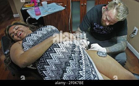 Tattoo artist Kolo Narvaez, 33, right, tattoos an orchid on the thigh of  Indiana University student Andrea Wilson, March 18, 2010, in Miami Beach,  Florida. Spring break brings a heavy amount of