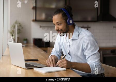 Close up motivated African American man wearing headphones watching webinar Stock Photo