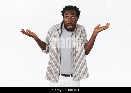 Embarrassed and awkward african-american bearded man trying to make excuses, shrugging with hands spread sideways clueless, looking puzzled and Stock Photo