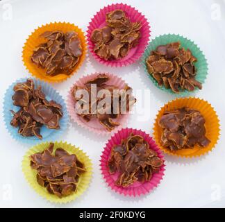 Chocolate crispy cakes in coloured paper cases against white background Stock Photo