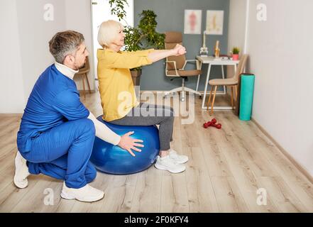 Senior woman doing treatment exercise at a rehab center with a male physiotherapist. Physio treatment for elderly people Stock Photo