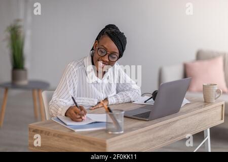 Cheerful business lady attending webinar, using laptop at home Stock Photo