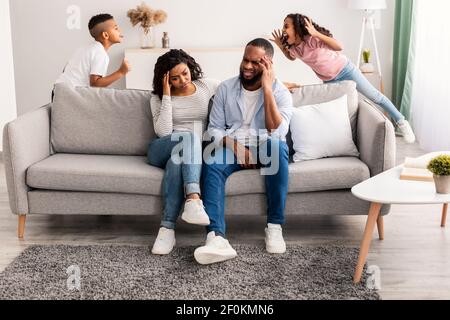 Black children fighting over their shocked parents Stock Photo