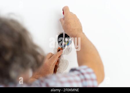 Electrician checking the presence of electrical current in the wires with a special tool. Stock Photo