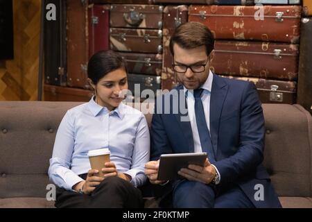 Close up diverse employees looking at tablet screen, discussing project Stock Photo