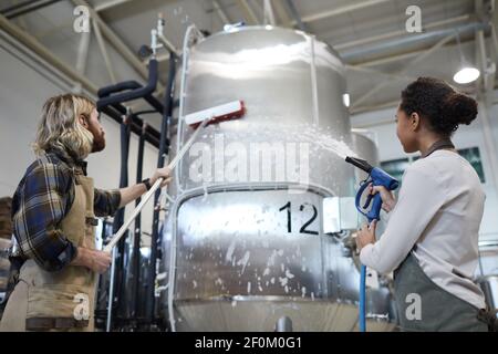 Low angle view at two workers washing equipment at modern industrial brewery, copy space Stock Photo