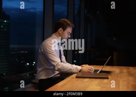 Side view confident businessman working on laptop at night Stock Photo
