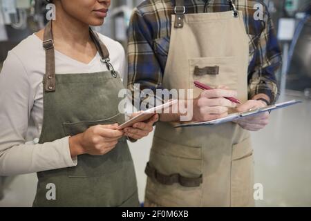 Cropped portrait of two young workers using digital tablet while supervising production at modern craft brewery, copy space Stock Photo