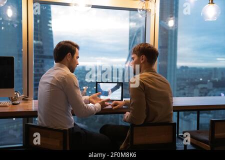 Rear view confident manager businessman consulting client, using laptop Stock Photo