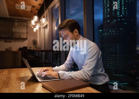 Close up focused businessman using laptop in office at night Stock Photo