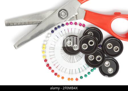 Close-up red pair of scissors with needle and large buttons isolated on white background. Sewing concept Stock Photo