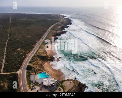 Aerial view of a beautiful isolated road with vehicles driving along south Portuguese coastline facing the Atlantic Ocean rough sea, Cascais, Portugal Stock Photo