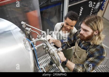 High angle view at two young workers operating brewing equipment at beer making factory, copy space Stock Photo