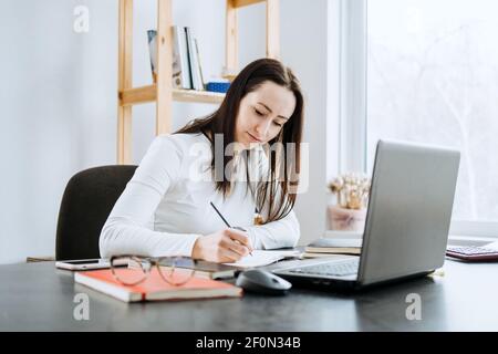 Remote Accounting Finance Jobs. Online Accounting Solution. Candid portrait of female accountant working with laptop, calculator and documents at home Stock Photo