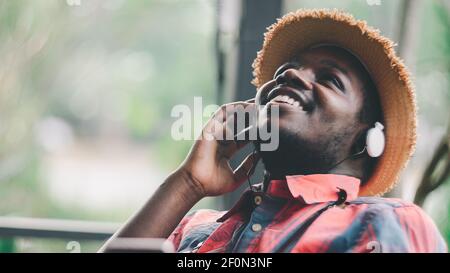 Emotional african traveler man  listening to music from smartphone with earphones Stock Photo