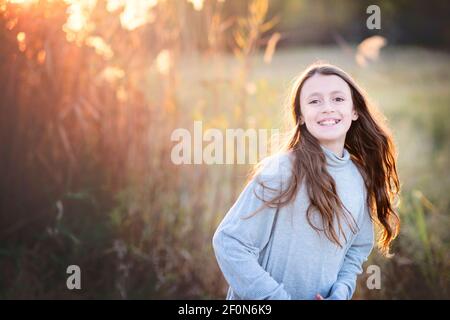 Backlit beautiful young tween girl with long hair outdoors in Fall. Stock Photo