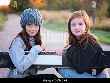 Two young tween girls in sweaters outdoors on country road. Stock Photo