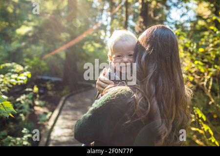 Happy boy looking over mothers shoulder. Stock Photo