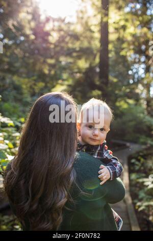 Rear view of mother holding son looking over her shoulder. Stock Photo