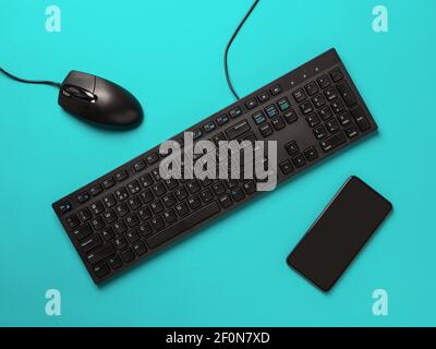 Black desktop computer keyboard, pc mouse and smartphone on a turquoise background. Modern devices and gadgets. Online business, learning, shopping. Stock Photo