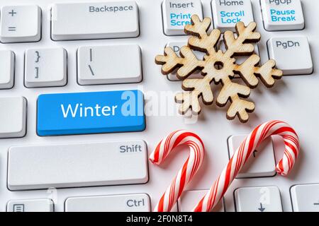 Blue key with Winter word, snowflake and candy canes on white pc keyboard. Winter sales, holidays, Christmas, New Year concepts. Message on enter key. Stock Photo