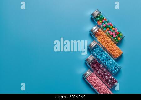 colored candies in jars on a blue background Stock Photo