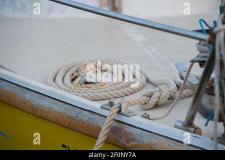 boat rope curled in circular formation on boat deck in cleat in Mallorca sailing travel vacation white rope yellow boat horizontal format type space Stock Photo