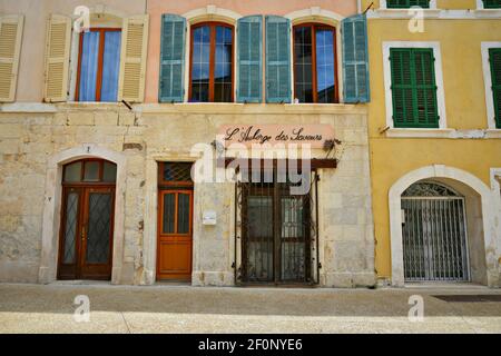 Old traditional hotel facade with ochre stucco walls colorful wooden window shutters and a handmade iron sign in Martigues Bouches-du-Rhône France. Stock Photo