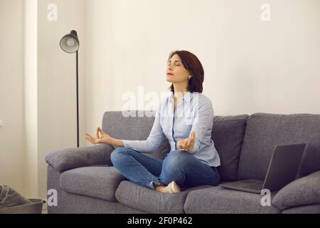 Caucasian middle age self-employed woman entrepreneur meditating on home sofa Stock Photo