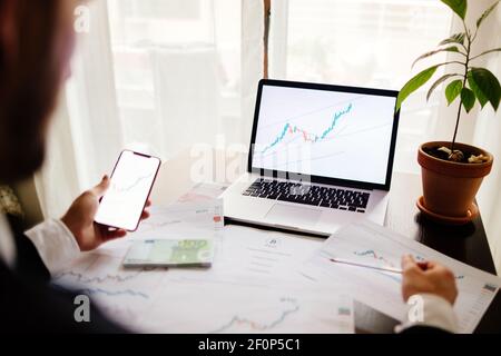 Investment broker trading bitcoin crypto currency using phone and laptop Stock Photo
