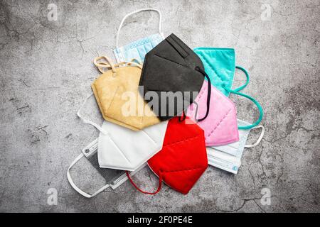 Multicolored surgical masks on gray background, top view. disposable medical face masks in different colors. COVID-19 pandemic Lockdown. Stock Photo