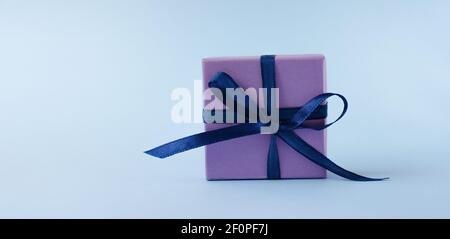 Purple colorful gift box with blue ribbon and bow on blue background.Copy space Stock Photo