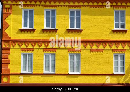 The facade of a house made of brick painted in yellow and windows, beautiful bright background Stock Photo