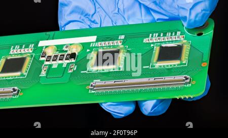 Detail of green printed circuit board in engineer hand. PCB with microchips and some electronic components in silicone paste for humidity protection. Stock Photo