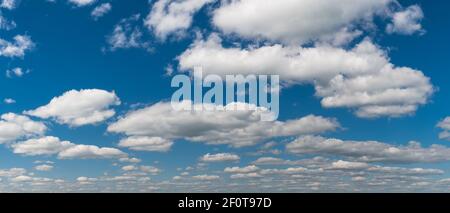 Beautiful white clouds on blue sky in panoramic background. Abstract cloudscape scenery with floating fluffy cumuli on azure heaven in scenic panorama. Stock Photo