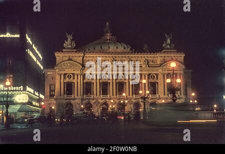 The façade of Palais Garnier from Place de l'Opéra at night. Paris, France, 1964 Stock Photo