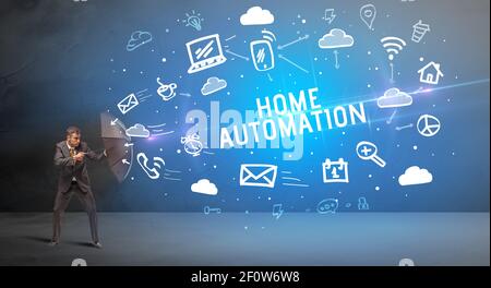 Businessman defending with umbrella from HOME AUTOMATION inscription, modern technology concept Stock Photo