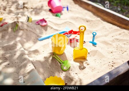Sandbox outdoor. Children's wooden sandbox with various toys for the game. Summer concept. Selective focus with shallow depth of field Stock Photo