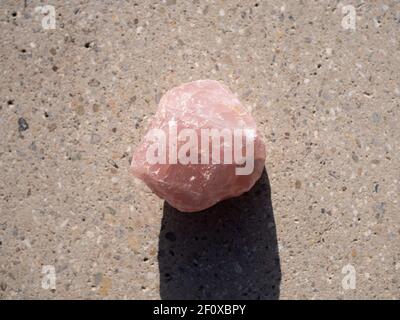 Pink quarz mineral stone on concrete surface. Stock Photo