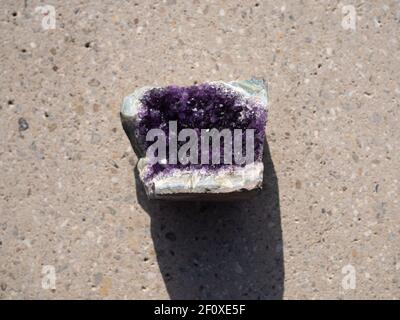 Amethyst mineral stone on concrete surface. Stock Photo