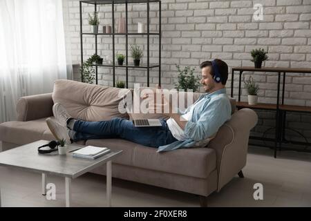 Smiling man in headphones speak by video call using laptop Stock Photo