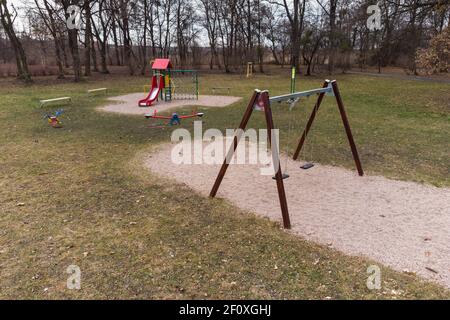 Lonely swing and slide at empty children playground. Stock Photo