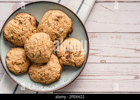 Close up top view on crunchy oatmeal chip cookies fresh baked biscuits with chocolate and cocoa in a plate on the table - homemade food concept copy s Stock Photo